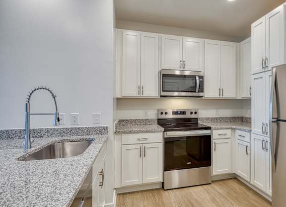 A kitchen with white cabinets and a stainless steel refrigerator.