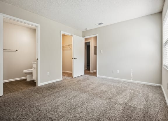 a bedroom with an open door and a bathroom in the background