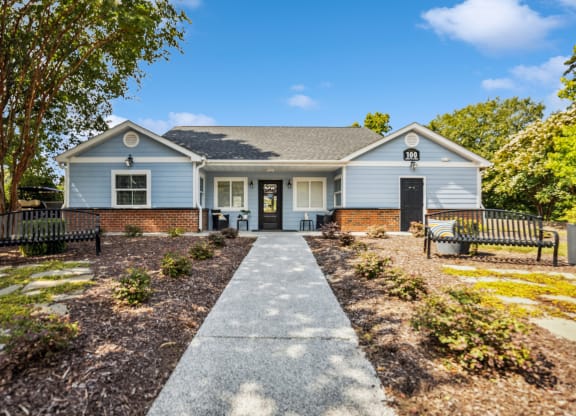 a blue house with a walkway and benches in front of it