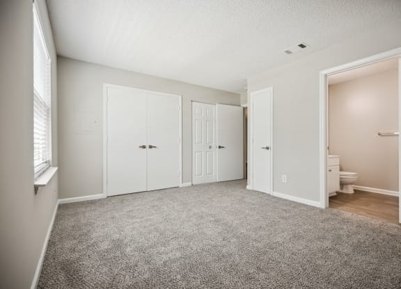 a bedroom with two doors and a bathroom in the background
