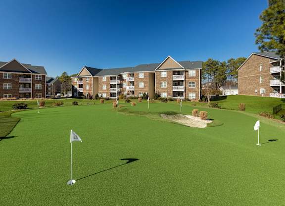 A golf course with a green lawn and two white flags on the tee.