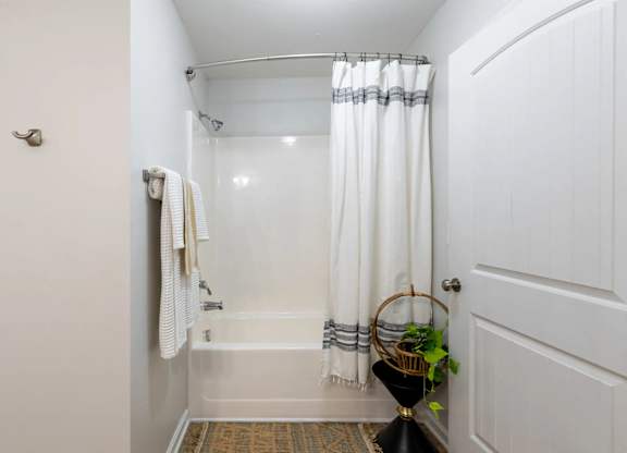 A white bathroom with a white tub and a white shower curtain.