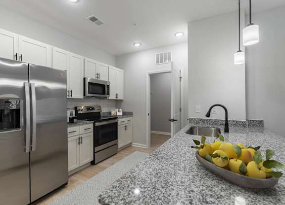 A kitchen with a granite countertop and a bowl of lemons on it.