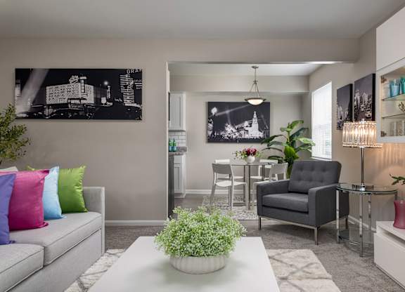 A living room with a grey couch, a black chair, a white coffee table, and a black and white photograph on the wall.