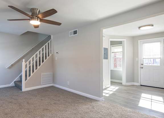 A room with a staircase and a ceiling fan.