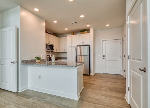 a kitchen with white cabinets and a granite counter top and a refrigerator at Allure at Edinburgh, Virginia