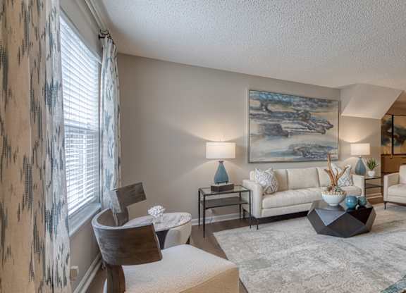 A living room with a large painting on the wall and a white couch.