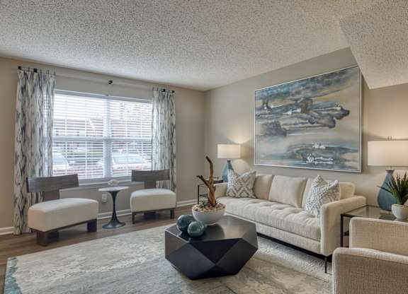 A living room with a large painting on the wall and a white sofa.
