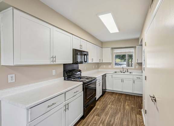 A kitchen with white cabinets and a black stove top oven.
