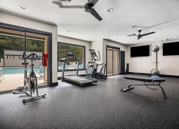 a home gym with a pool in the background