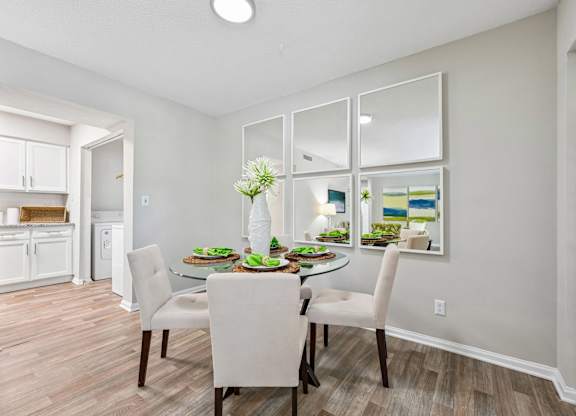 A dining room with a table set for two and a kitchen area in the background.