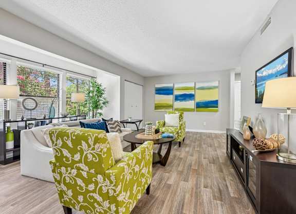 A living room with a green patterned chair and a painting on the wall.