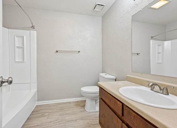 A white toilet sits in a bathroom next to a sink and a shower.