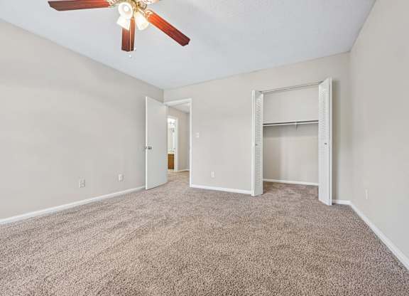 A room with a ceiling fan and carpeted floor.