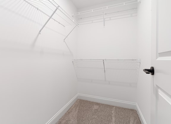a walk in closet with white walls and white shelves and a white door at The Madison, Columbus, Ohio
