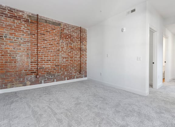 an empty room with a brick wall and white carpet at The Madison, Columbus