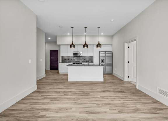 A modern kitchen with a white island and pendant lights.