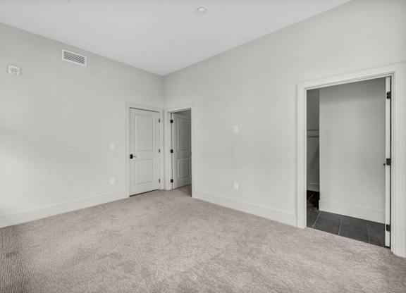 A room with a carpeted floor and two doors.