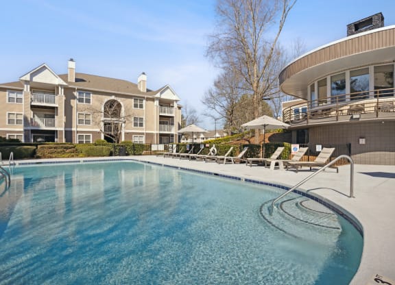 a large pool with chairs and a building in the background