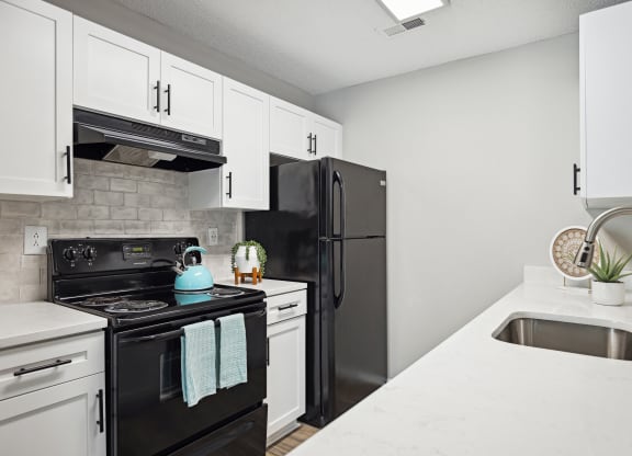 an apartment kitchen with black appliances and white cabinets