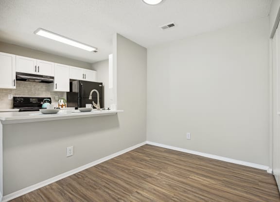 an empty kitchen and living room with white walls and wood flooring