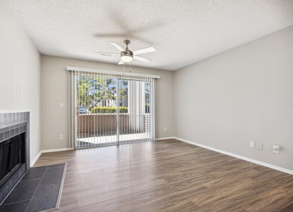 an empty living room with a fireplace and a ceiling fan