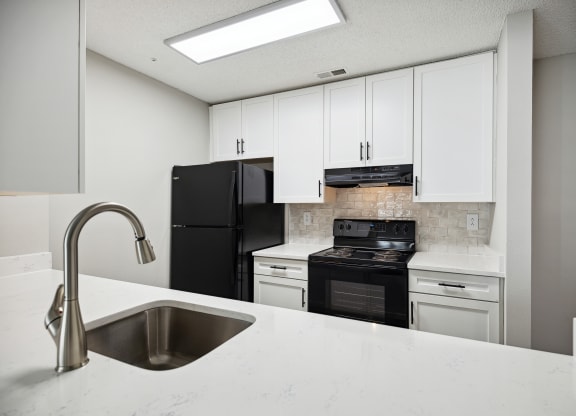 a kitchen with white cabinets and black appliances and a sink