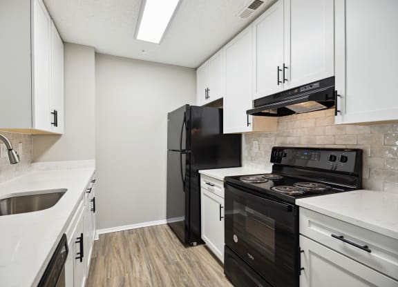 an empty kitchen with white cabinets and a black stove and refrigerator
