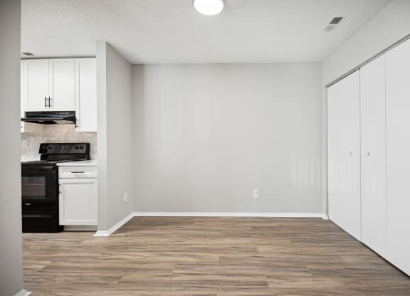 an empty kitchen with white cabinets and a wood floor