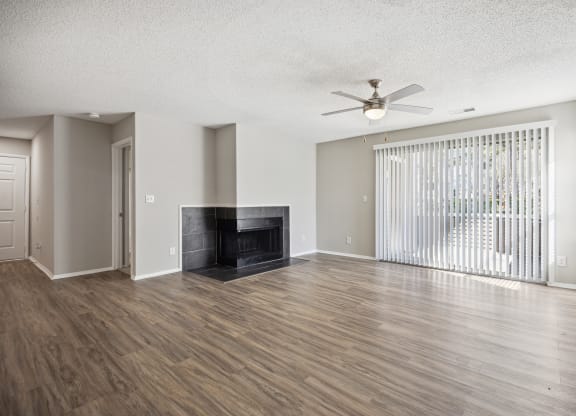 an empty living room with a fireplace and a ceiling fan