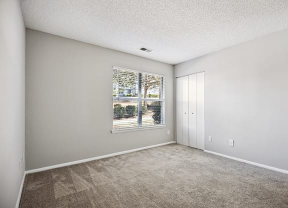 an empty living room with a large window and carpeting