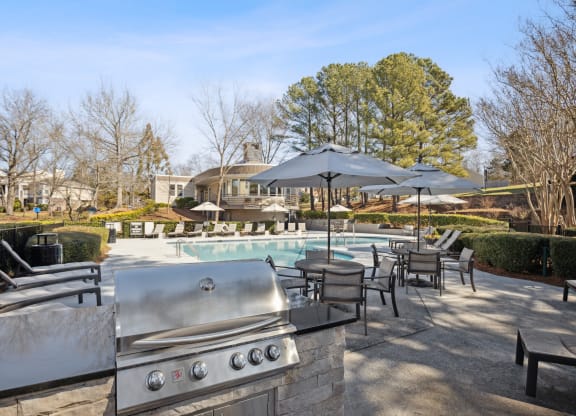 an outdoor patio with a pool and chairs and umbrellas