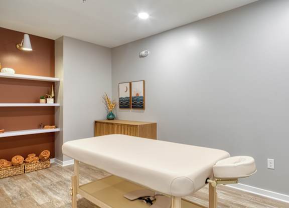 A massage table in a room with a shelf and towels.