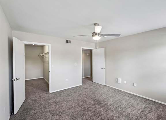 A spacious room with a ceiling fan and carpeted floor.