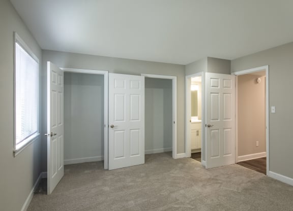a bedroom with three doors and a carpeted floor
