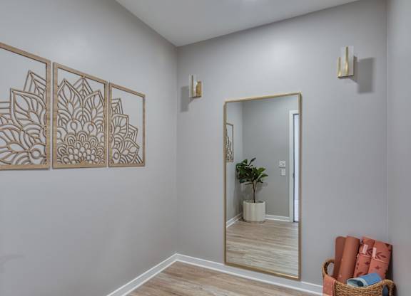 A room with a mirror, a plant, and a wall art.