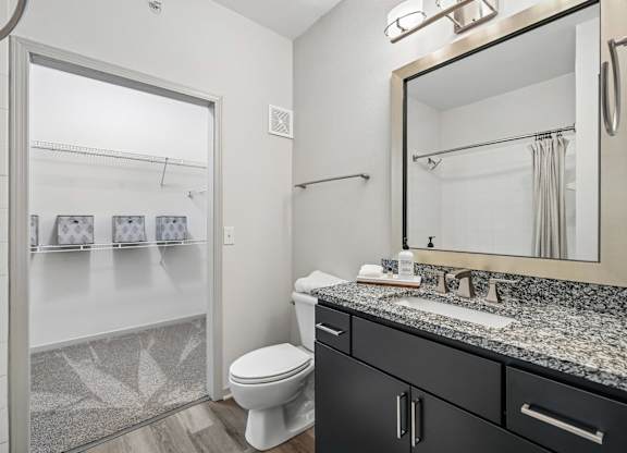 A bathroom with a toilet, sink, and mirror.
