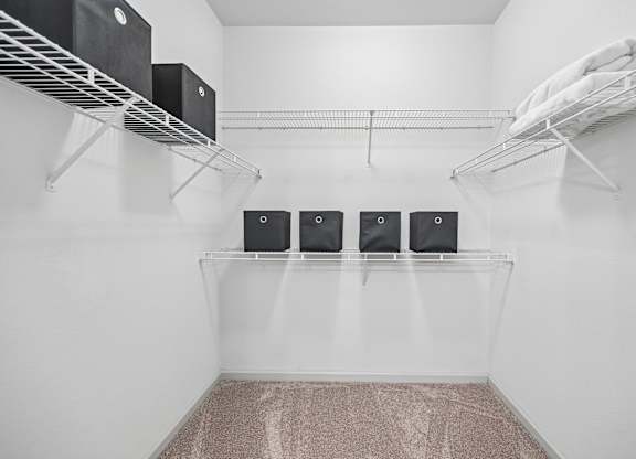 A laundry room with a carpeted floor and a metal rack holding dryers and towels.