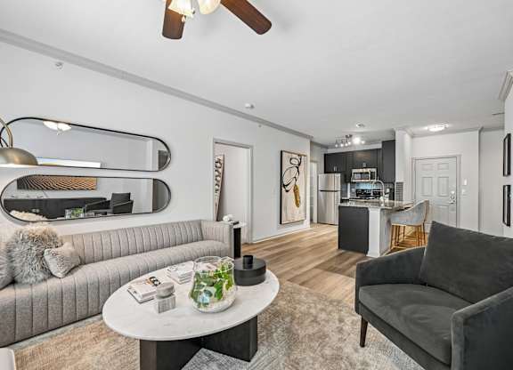 A modern living room with a grey sofa, a round table, and a ceiling fan.