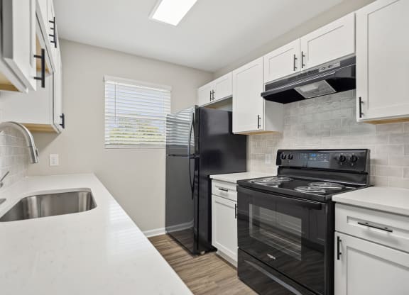 an empty kitchen with white cabinets and black appliances