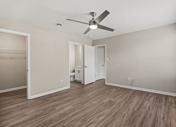 an empty living room with a ceiling fan and a bathroom