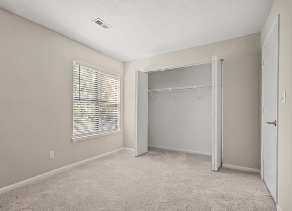 an empty bedroom with a closet and a window