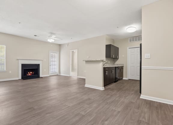 an empty living room with a fireplace and a kitchen
