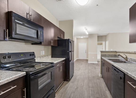 an empty kitchen with black appliances and granite counter tops