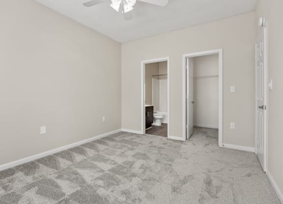 an empty living room with a ceiling fan and a door to a bathroom