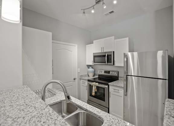 A kitchen with a sink, stove, and refrigerator.