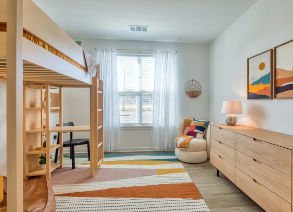 a bedroom with bunk beds and a desk and a window