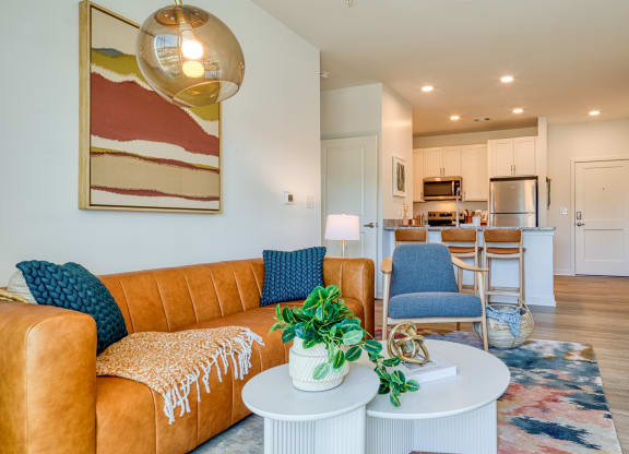 a living room with a couch and a table in front of a kitchen