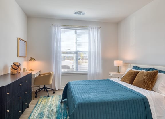 a bedroom with a bed and a desk and a window