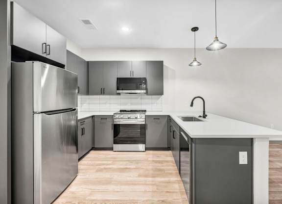 A modern kitchen with stainless steel appliances and wooden flooring.
